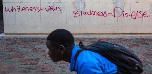 Estudante passa por pichação durante protestos em Johannesburgo, África do Sul - João Silva/The New York Times