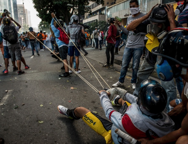 Manifestantes se preparam para disparar "bombas" com fezes ou tinta contra a polícia em Caracas, na Venezuela - Meridith Kohut/The New York Times