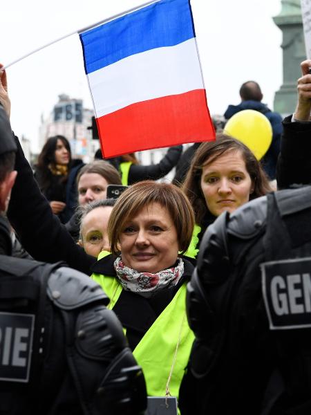 Mulher segura bandeira da França em frente a policiais franceses durante protesto - Bertrand Guay/AFP