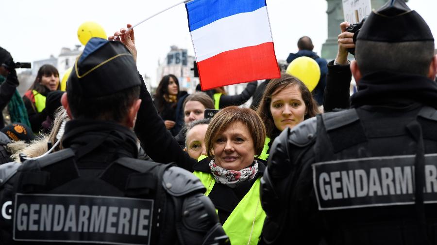 6.jan.2019 - Mulher segura bandeira da França em frente a policiais franceses durante protesto dos "coletes amarelos" em Paris - Bertrand Guay/AFP