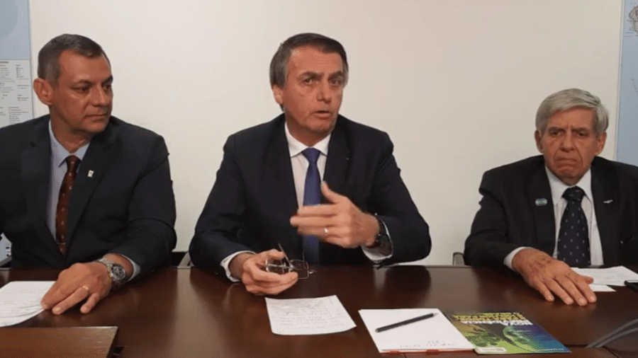 O presidente Jair Bolsonaro (centro), o general Augusto Heleno (à dir.) e porta-voz da Presidência, Otávio Rêgo Barros, durante transmissão ao vivo no Facebook - Redes sociais / Reprodução