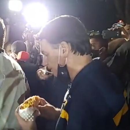 Jair Bolsonaro come cachorro-quente em meio a apoiadores durante passeio em Brasília - Facebook/Reprodução