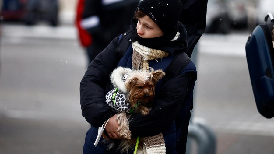 Criança fugindo da invasão russa da Ucrânia segurando cachorro durante uma queda de neve - Reuters