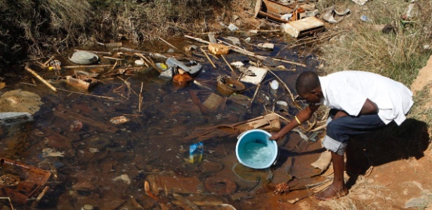 Homem coleta água em lugar sem tratamento em Harare, capital do Zimbábue