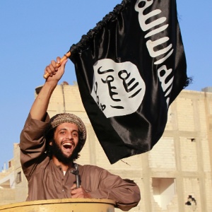 Militante islâmico balança bandeira do Estado Islâmico em Raqqa, na Síria - Reuters