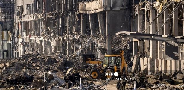 21.mar.2022- Bombeiros ucranianos trabalham ao lado de um escavador em meio aos escombros do shopping Retroville, um dia depois de ter sido bombardeado pelas forças russas em um distrito residencial no noroeste da capital ucraniana Kiev.