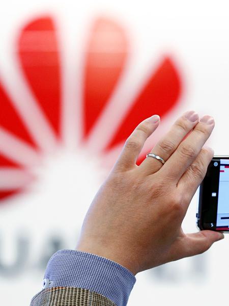 Homem tira foro do logotipo da Huawei estampado no Centro de Cibersegurança da empresa em Bruxelas