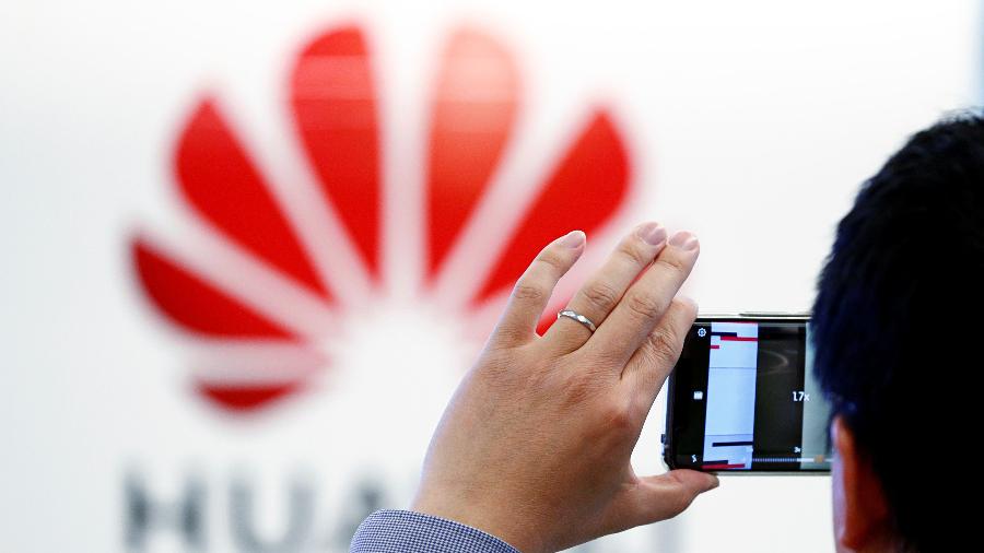 Homem tira foro do logotipo da Huawei estampado no Centro de Cibersegurança da empresa em Bruxelas - François Lenoir/Reuters