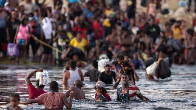 Imigrantes haitianos atravessam o Rio Grande, na divisa dos EUA com o México, temendo deportação