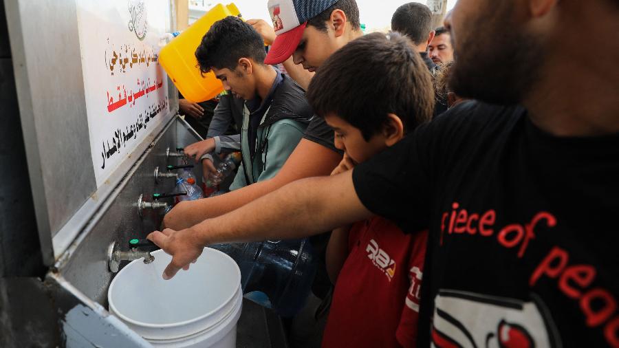 Palestinos fazem fila para encher baldes de água na Cidade de Gaza, em meio a cerco de Israel