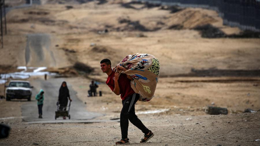 Palestinianos transportam os seus pertences enquanto se preparam para fugir de Rafah, no sul da Faixa de Gaza, em 13 de maio de 2024 - -/AFP