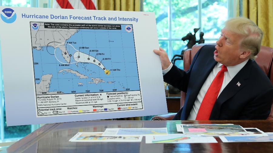 Donald Trump expõe um cartaz com uma linha preta junto ao desenho oficial da trajetória do furacão Dorian - JONATHAN ERNST / REUTERS
