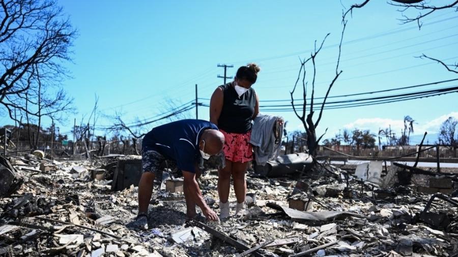 Moradores procuram por bens no meio das cinzas da casa dos familiares após incêndios em Lahaina, no Havaí