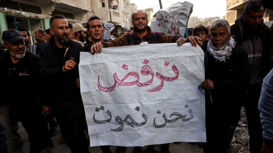Palestinos seguram placa dizendo "nos recusamos a morrer", em protesto em Beit Lahia Palestinos seguram placa dizendo "nos recusamos a morrer", em protesto em Beit Lahia