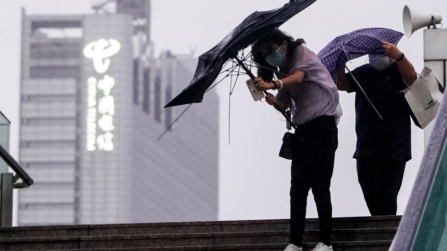 Pedestres tentam segurar guarda-chuvas em meio aos fortes ventos em Xangai, com a chegada do tufão Chanthu - REUTERS/Aly Song