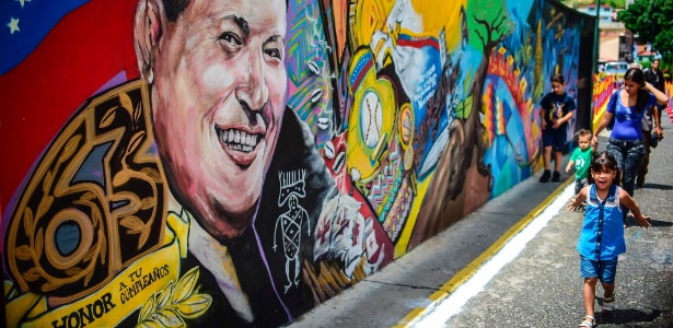 Crianças passam por mural com o rosto do presidente Hugo Chávez - Ronaldo Schemidt/Reuters