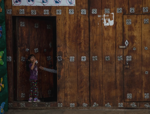 Menina bebe uma lata de refrigerante na saída da igreja, em San Juan Chamula, no México - Adriana Zehbrauskas/The New York Times