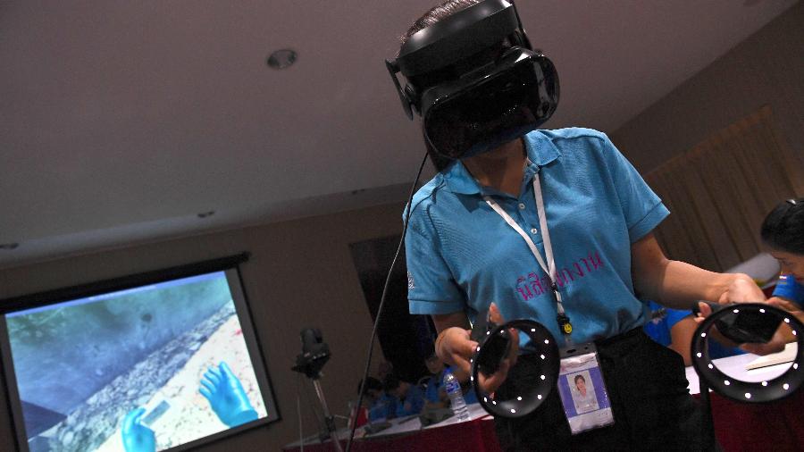 Policial forense tailandesa usa headset de realidade virtual para procurar vítimas em uma cidade simulada em ruínas na sede da polícia na província de Chonburi - Lillian Suwanrumpha/AFP
