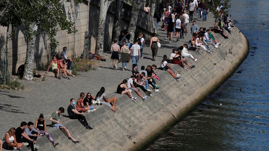 Pessoas se sentam nas margens do Rio Sena, na França, após o país gradualmente relaxar medidas de confinamento pelo coronavírus - Gonzalo Fuentes/Reuters