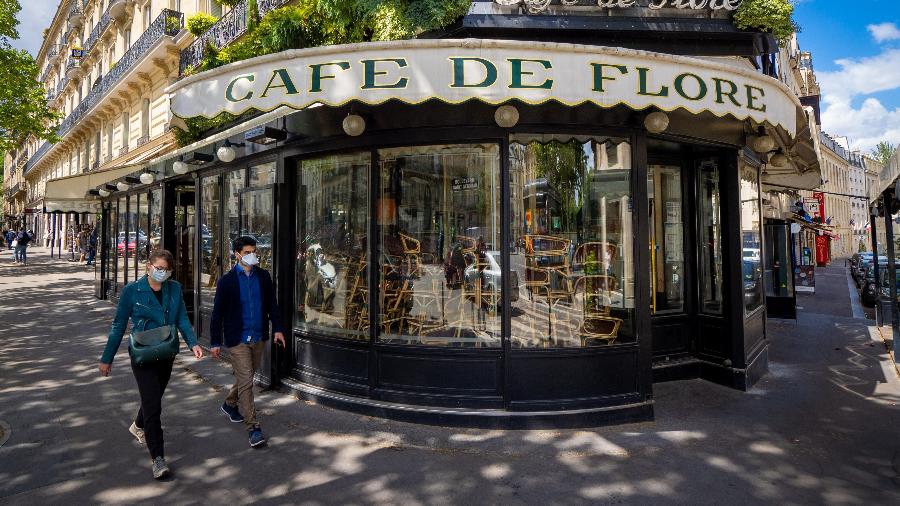 Franceses usando máscaras de proteção passam em frente a um restaurante na capital do país, Paris - Getty Images