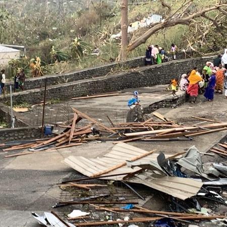 Moradores sentados em uma estrada entre pilhas de escombros Moradores sentados em uma estrada entre pilhas de escombros