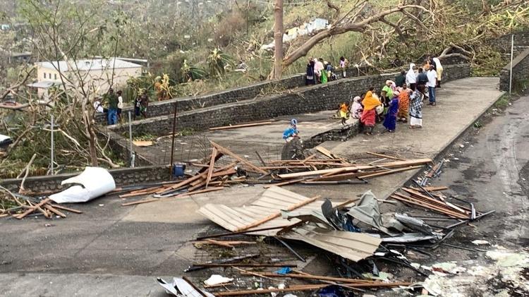 15.dez.2024 - Moradores sentados em uma estrada entre pilhas de escombros de chapas de metal e madeira depois que o ciclone Chido atingiu o território francês do Oceano Índico de Mayotte