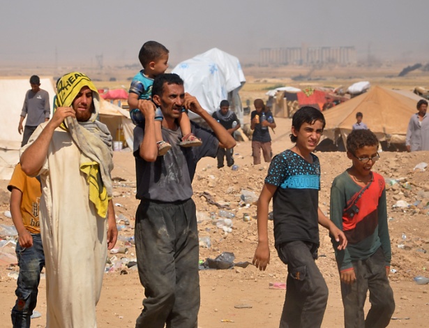 Sírios fugidos de Deir Ezzor caminham em acampamento no meio do deserto, dominado por jovens que fugiram do recrutamento do EI - AYHAM AL-MOHAMMAD/AFP