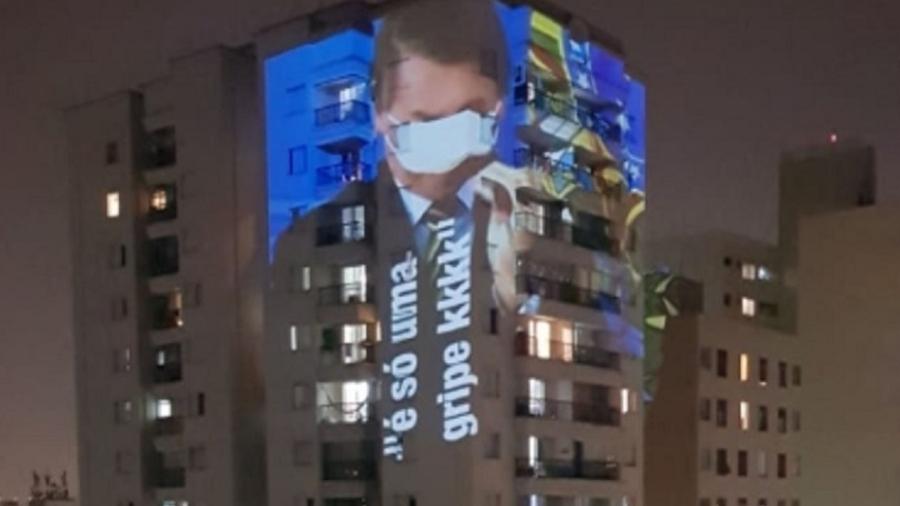 Imagem de Bolsonaro com máscara fazendo as vezes de venda é projetada em prédio no bairro de Santa Cecília, em São Paulo, durante panelaço e buzinaço contra o presidente  - Reprodução