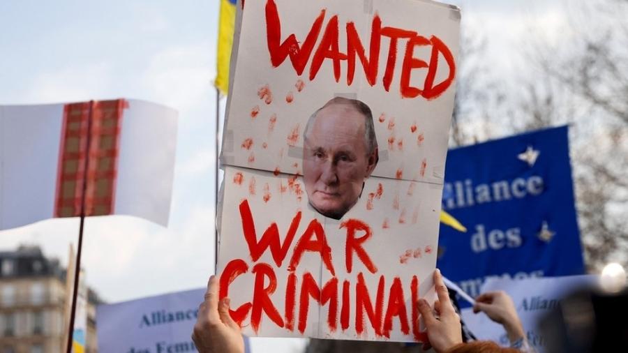 Manifestante em Paris segura cartaz acusando Vladimir Putin de crimes de guerra - Reuters