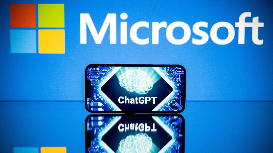 Logotipo da Microsoft com um celular exibindo um logotipo do ChatGPT, chatbot inteligente desenvolvido pela OpenAI - Lionel Bonaventure/AFP
