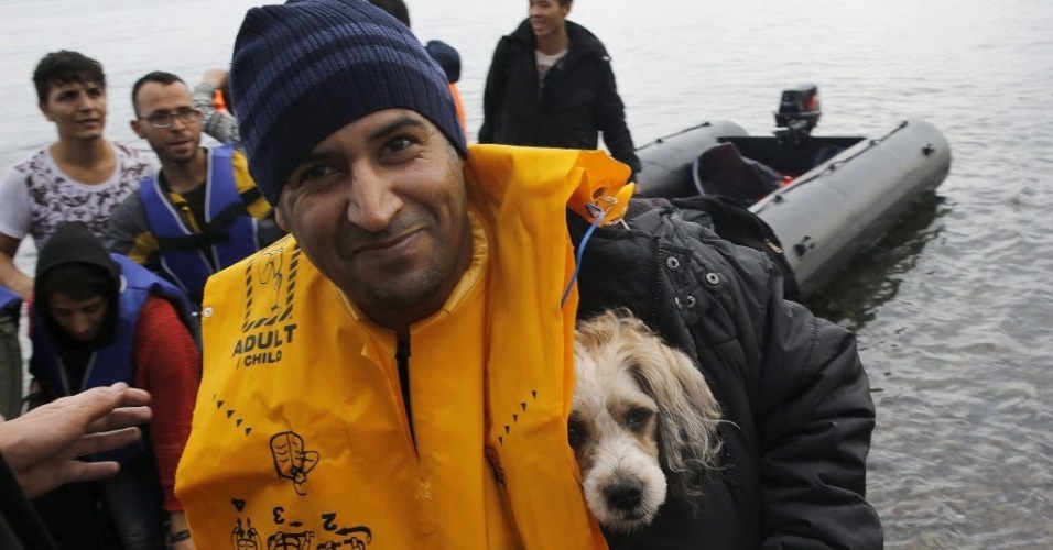 24.set.2015 - Imigrante afegão carrega cão no seu colete salva-vidas após chegar à ilha grega de Lesbos em um bote superlotado depois de atravessar parte do mar Egeu, vindo da Turquia