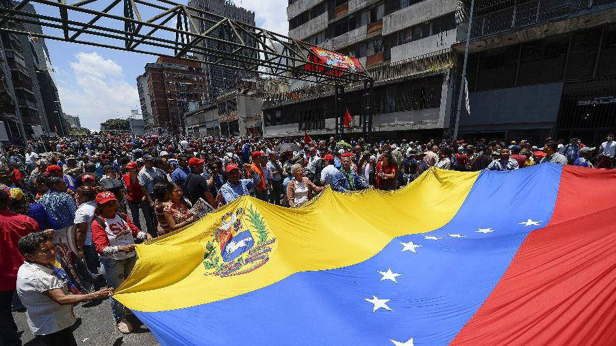 Apoiadores de Nicolás Maduro exibem uma bandeira da Venezuela durante ato em apoio ao presidente  - Matias Delacroix/AFP