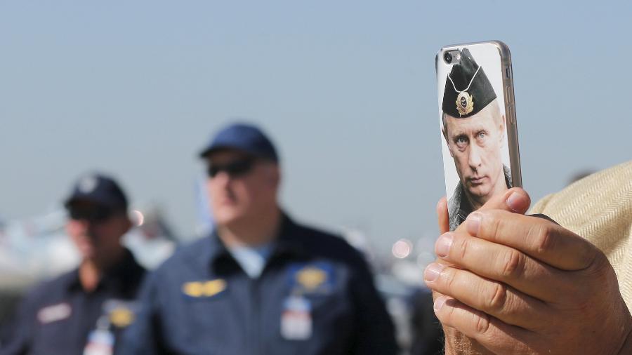 25.ago.2015 - Visitante exibe celular com imagem do presidente russo, Vladimir Putin, estampada na capa, durante o Salão Internacional de Aviação e Espaço em Zhukovsky, nos arredores de Moscou - Maxim Shemetov/Reuters