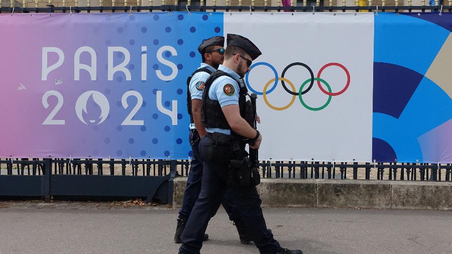Patrulha policial em frente à Assemblee nationale (Assembleia Nacional) passando por um cartaz publicitário dos Jogos Olímpicos de Paris 2024 em Paris, França, 29 de junho de 2024 - Fabrizio Bensch/REUTERS