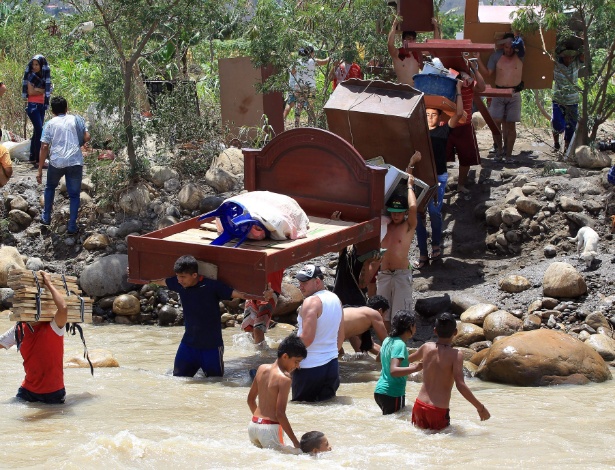 Colombianos despejados carregam seus pertences ao cruzar o rio Táchira, saindo da Venezuela em direção ao setor de La Parada, na Colômbia, em Cúcuta - Mauricio Dueñas Castañeda/EFE