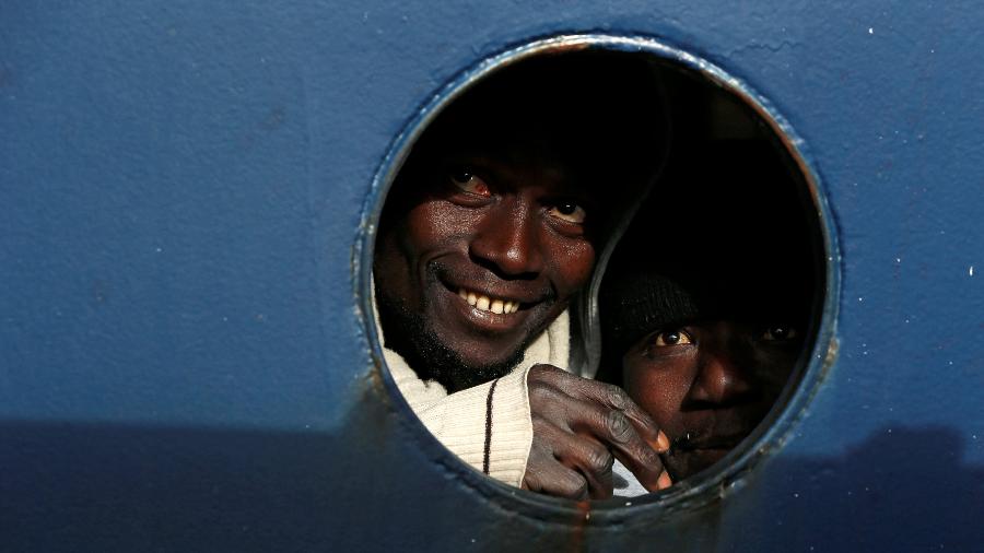 Imigrantes olham para fora do convés de um navio de busca e salvamento - DARRIN ZAMMIT LUPI/Reuters