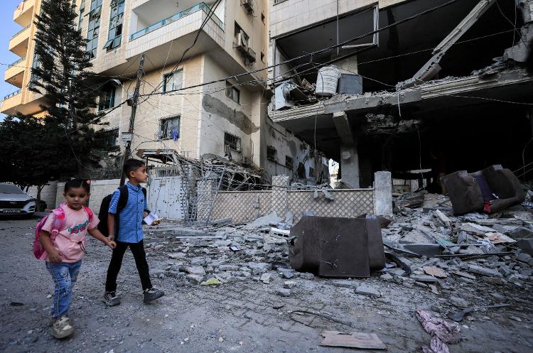 03.out.26 - Crianças palestinas passam pelo local de um ataque israelense a um prédio de apartamentos na Cidade de Gaza
