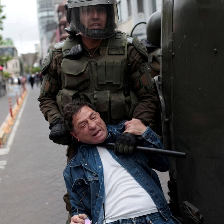 Policial usa bastão para deter manifestante pelo pescoço durante protestos em Concepción, no Chile - Juan Gonzalez/Reuters