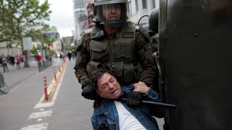 19.out.2019 - Policial usa bastão para deter manifestante pelo pescoço durante protestos em Concepción, no Chile - Juan Gonzalez/Reuters