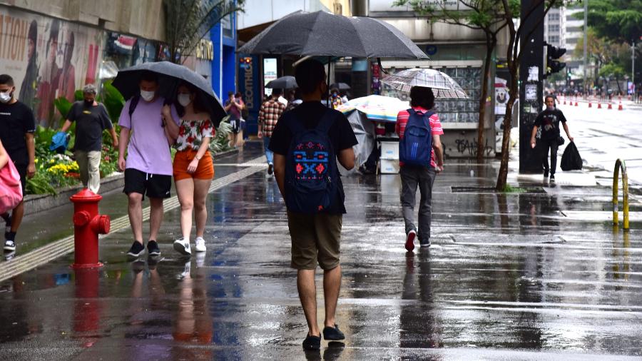 Pessoas andam com guarda chuva na Av. Paulista
