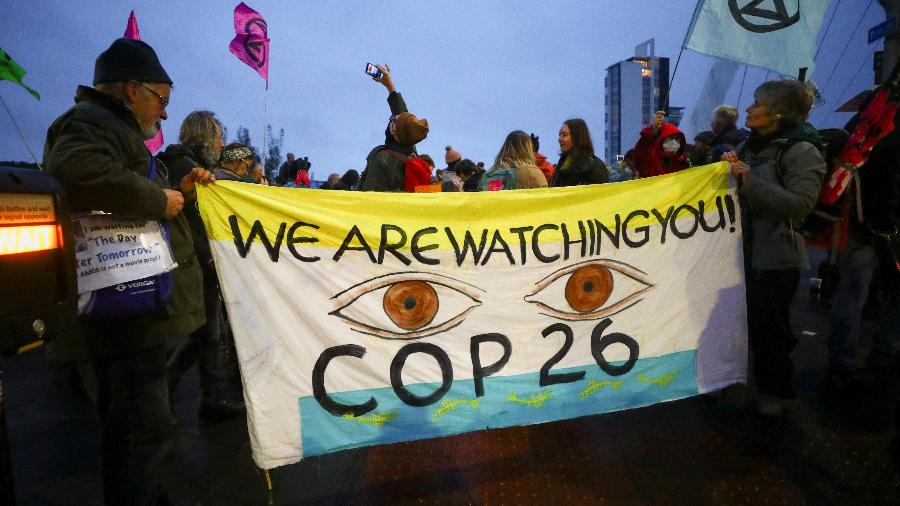 Ativistas seguram uma faixa em protesto na COP26 em Glasgow, na Escócia - HANNAH MCKAY/REUTERS
