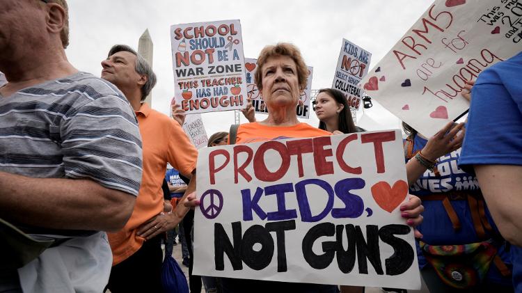 A woman has a sign on it that says "Save the Children, Not the Guns" - REUTERS/Ken Cedeno - REUTERS/Ken Cedeno