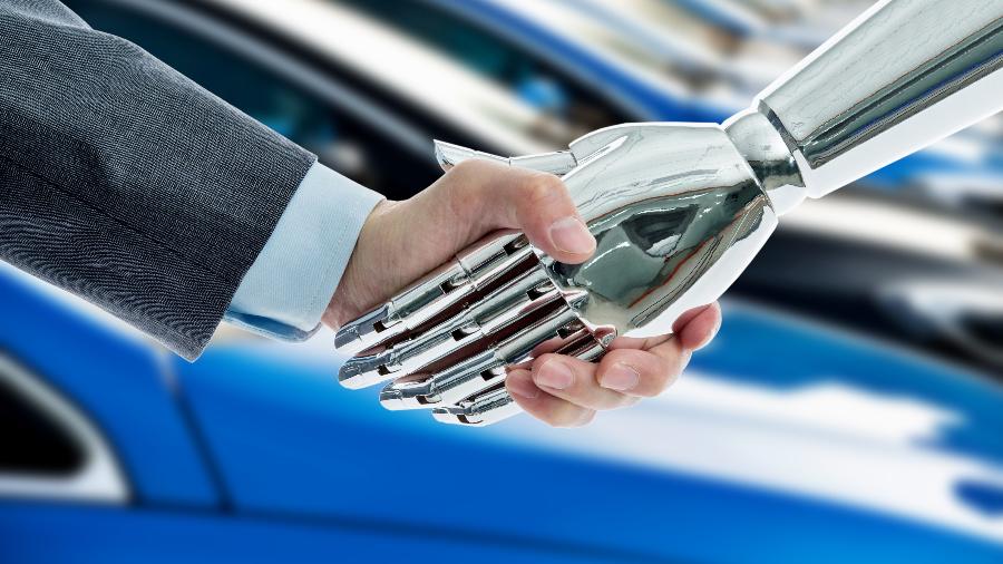 Humano e robô se cumprimentam à frente de carros azuis - Getty Images/iStockphoto