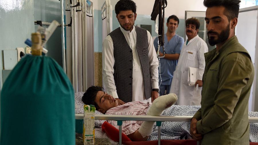 Um homem ferido recebe tratamento enquanto amigos se reúnem em torno dele  após uma explosão em um salão de festas em Cabul - WAKIL KOHSAR / AFP