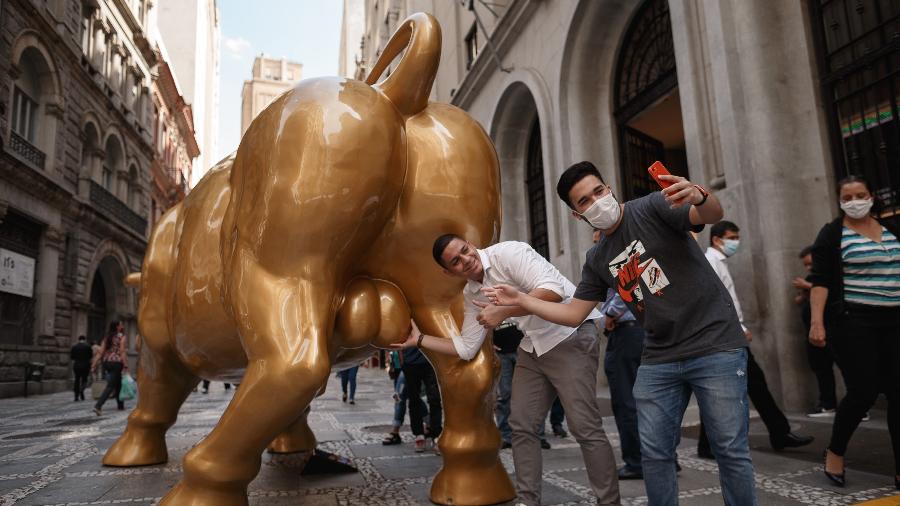 Pessoas tiram fotos junto do "Touro de Ouro", escultura inaugurada em frente à sede da B3 - Ettore Chiereguini/Agif/Estadão Conteúdo