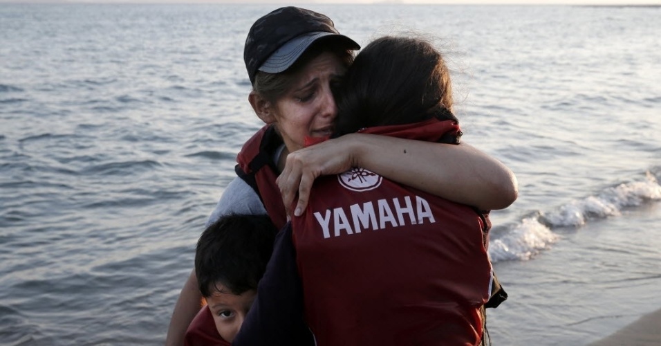 18.ago.2015 - Mãe abraça seus filhos após chegar em um bote na ilha grega de Kos. Quase 110 mil imigrantes entraram na União Europeia em julho, estabelecendo um novo recorde, de acordo com dados da Frontex, agência de controle das fronteiras da UE. Sírios e afegãos, fugindo da instabilidade de seus países, representam a maioria dos imigrantes