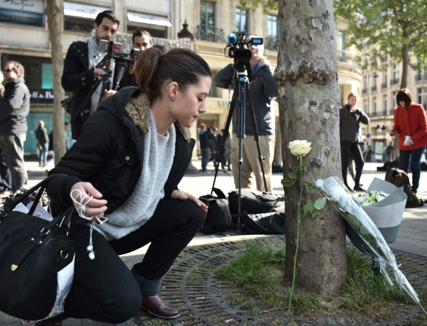 Mulher deposita uma flor no local onde ocorreu o tiroteio na avenida Champs-Élysées - Philippe Lopez/APF Photo