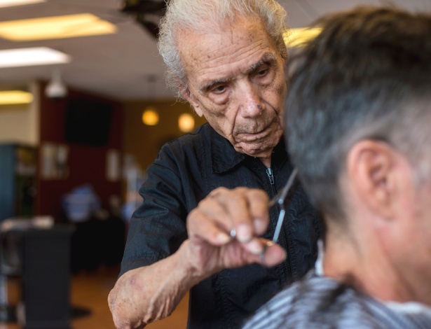 Anthony Mancinelli, de 107 anos, corta o cabelo de um cliente em um salão de cabeleireiro em New Windsor - Andrew Seng/The New York Times
