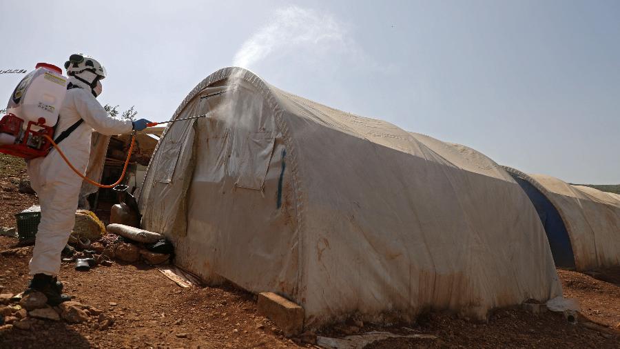 24.mar.2020 - Integrante da defesa civil da Síria desinfeta barraca no campo de refugiados de Kafr Lusin - AAREF WATAD / AFP