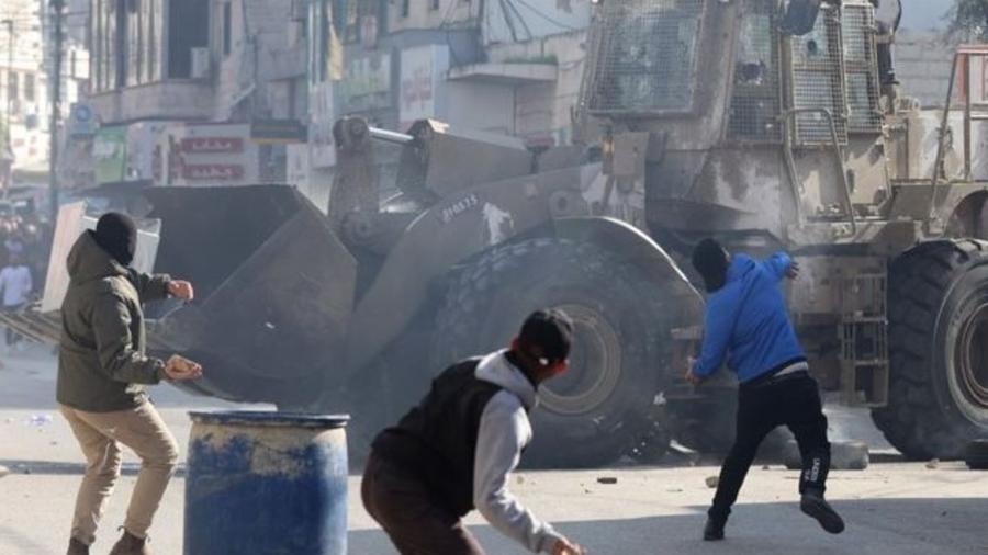 Palestinos jogam pedras em meio a confrontos com tropas israelenses durante um ataque em Jenin - EPA